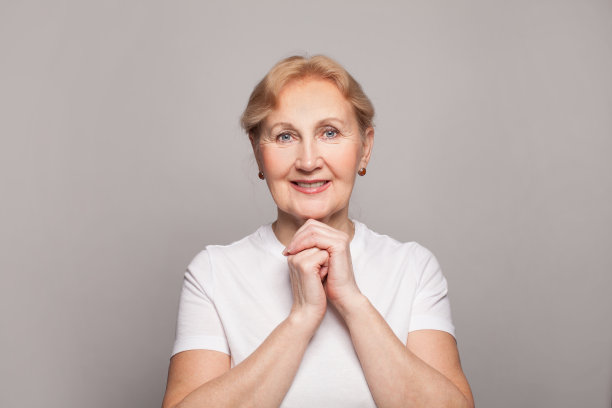 美丽的中年妇女微笑在灰色的墙壁背景图片下载