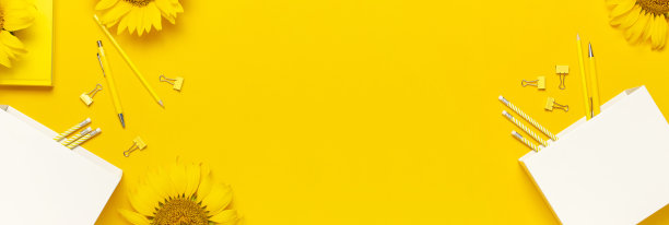 俯视图平的工作桌风格设计与向日葵，白色纸袋，铅笔，钢笔，回形针在明亮的黄色背景。秋季或夏季概念。向日葵自然背景图片下载