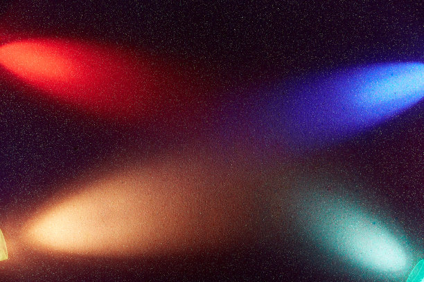 在一个深紫色梯度背景，交叉光束的蓝色，红色奶油色和绿松石梯度光图片下载