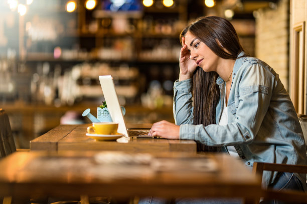 无聊的年轻女子在咖啡馆用笔记本电脑学习。图片下载