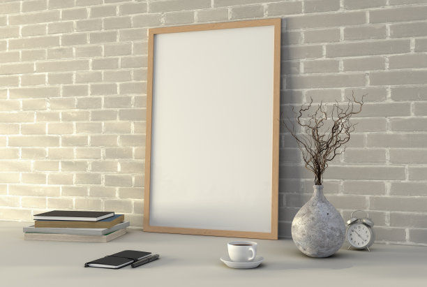 垂直木制图片海报框架模型。白色的桌子上放着咖啡、书、花瓶和笔记本。白色砖墙背景。图片下载