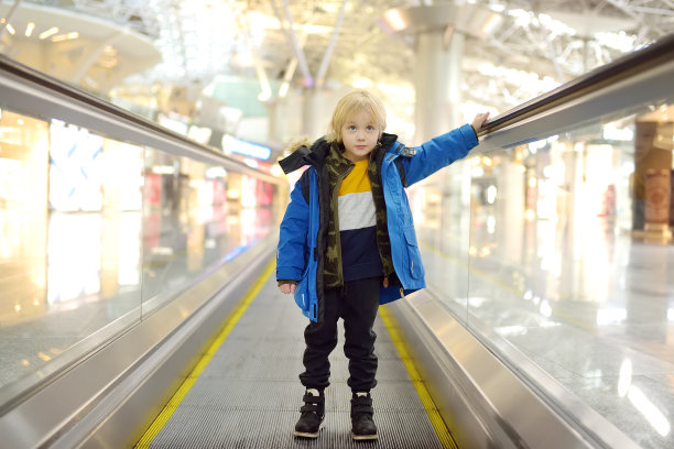国际机场高速人行道上的小旅客。寒假家庭旅行。孩子们的假期。图片下载