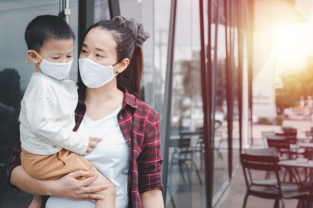 冠状病毒covid-19概念。亚洲小男孩和母亲一起戴口罩，在外生活，防止感染冠状病毒。冠状病毒后的新常态生活方式。图片下载