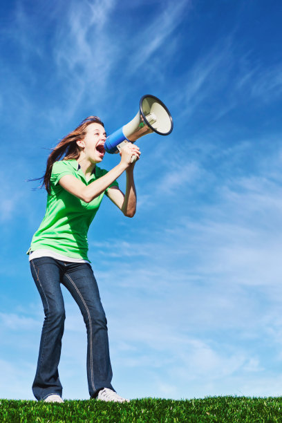 一个年轻女子对着夏天的天空对着扩音器大喊图片下载