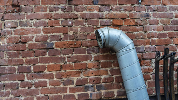 建筑外墙上的灰色金属风扇管。房屋翻新期间的旧通风系统。图片下载