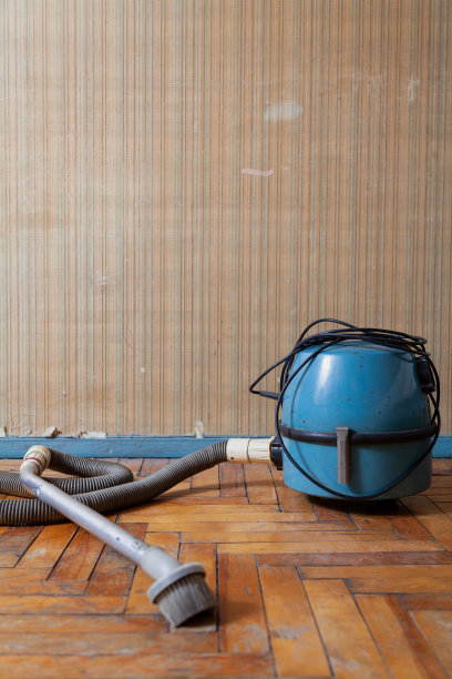 破旧的镶木地板上放着蓝色的吸尘器图片下载