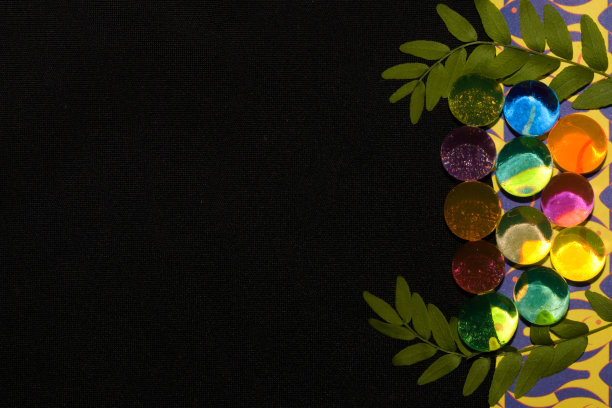 彩色复古壁纸，透明玻璃珠反射两根树枝的光，旁边的一片叶子作为复制空间的背景的黑色部分图片下载