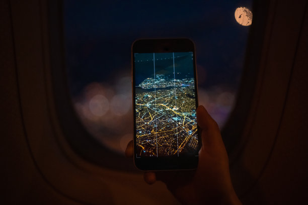 乘客用智能手机通过飞机窗户拍风景照片图片下载