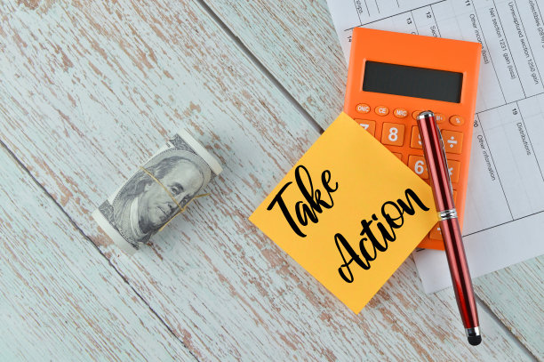 笔、计算器、钞票和便笺的俯视图，上面写着“采取行动”图片下载