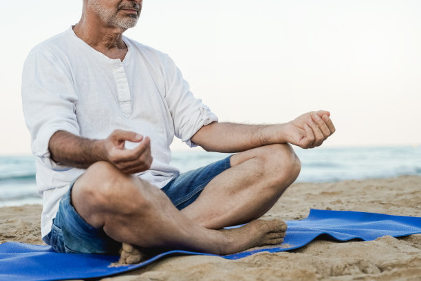 老年男人在海滩背景下进行户外瑜伽冥想——专注于右臂图片下载