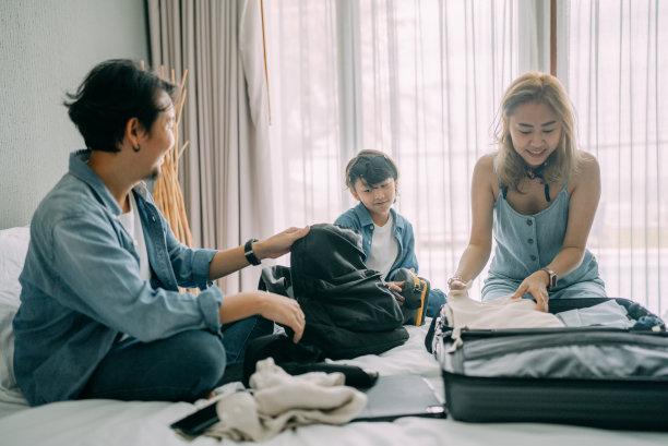 亚洲家庭在酒店房间床上打包布袋图片下载