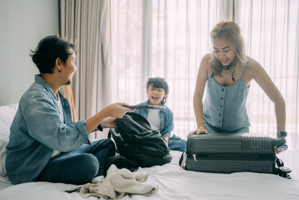 亚洲家庭在酒店房间床上打包布袋图片下载