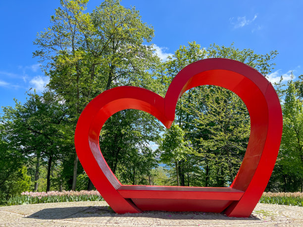 在一个阳光明媚的日子里，公园里绿树成荫的大红心和美丽的蓝天图片下载