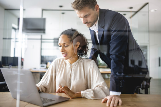 白人商人帮助他的拉丁同事，使用笔记本电脑图片下载