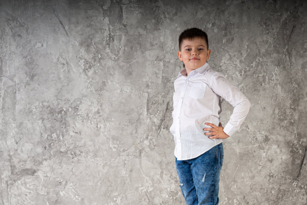 一个站在椅子上的小男孩的肖像，孤立在画室的白色背景上。图片下载