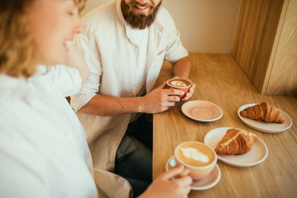 幸福的情侣坐在咖啡馆里，喝着咖啡，吃着羊角面包。图片下载
