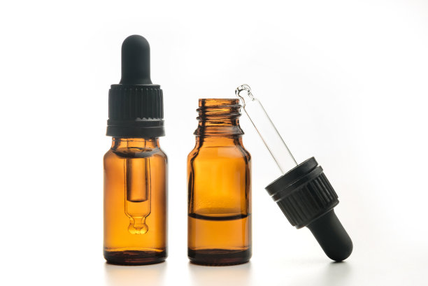 一对瓶子的精油隔离在一个白色的背景。图片下载