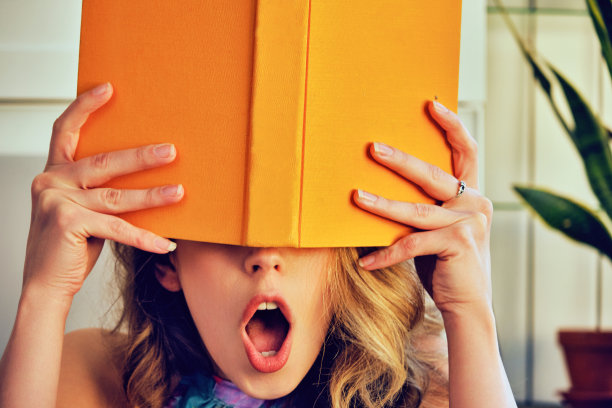 年轻震惊的大学女子手里拿着书盖着脸图书馆图片下载