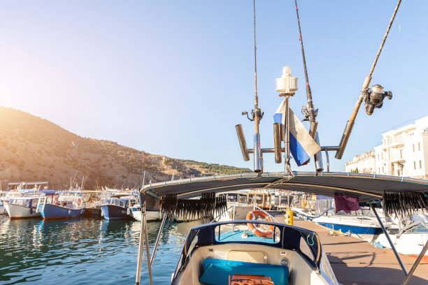 阳光明媚的日子里，停泊在渔村滨海湾的小船下，许多鱼竿和晒鱼的特写镜头。海港与传统复古船舶的背景图片下载