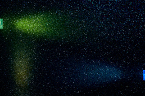 在一个小的多色颗粒的黑暗背景上，光线淡绿色和蓝色的光图片下载