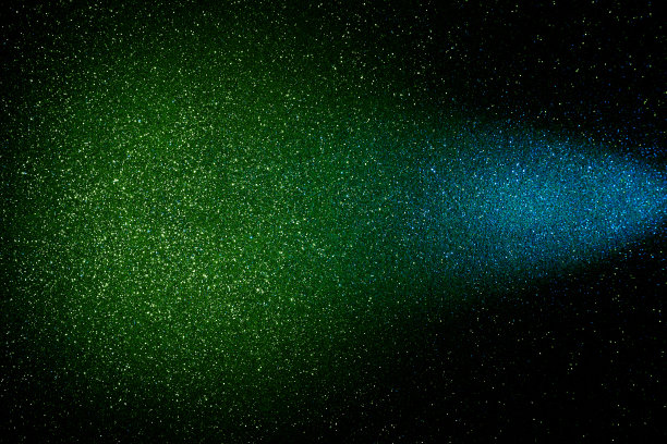 在黑色的背景上，细粒蓝色的光线过渡到绿色的光云图片下载
