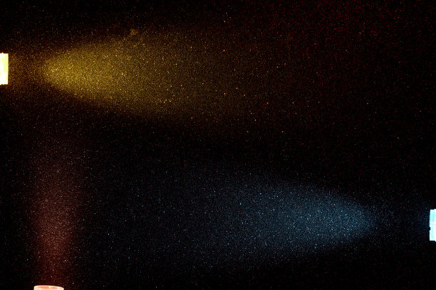 在一个小的多色颗粒的黑暗背景，光线黄绿松石和红色的光图片下载