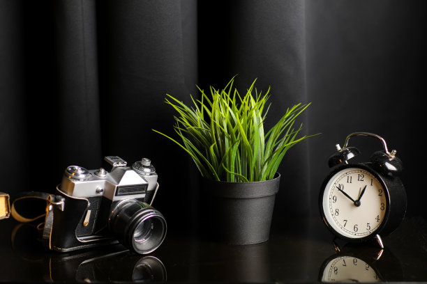 办公室创意办公桌与相机，时钟，书籍和室内植物在黑色的桌子。高质量的照片图片下载