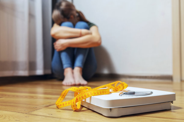 白色的鳞片和沮丧，不安和悲伤的女人用卷尺在木地板上图片下载