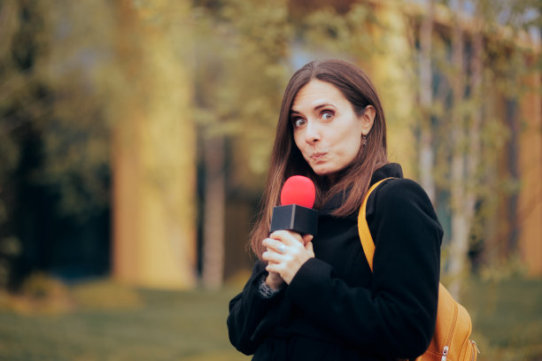 滑稽害羞的记者手持麦克风在现场直播图片下载