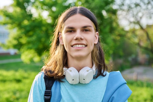 户外肖像英俊的学生男子与背包看相机图片下载