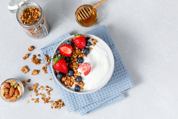 自制燕麦粥碗，浅灰色的背景上有浆果，蜂蜜和坚果。健康的食物图片下载