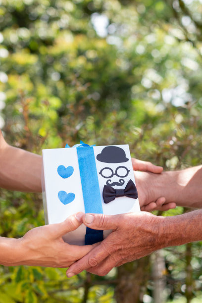 垂直的照片，一个年轻人给他的父亲有一个老人的手礼物。图片下载