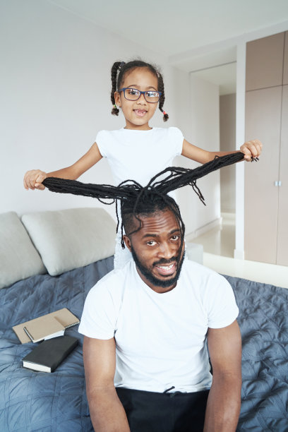 一个非裔美国女孩站在父亲身后的床上图片下载