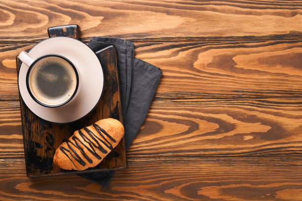 咖啡和羊角面包。旧木桌上放着浓缩咖啡和巧克力羊角面包。完美的羊角面包早餐。乡村风格。前视图。模拟。图片下载