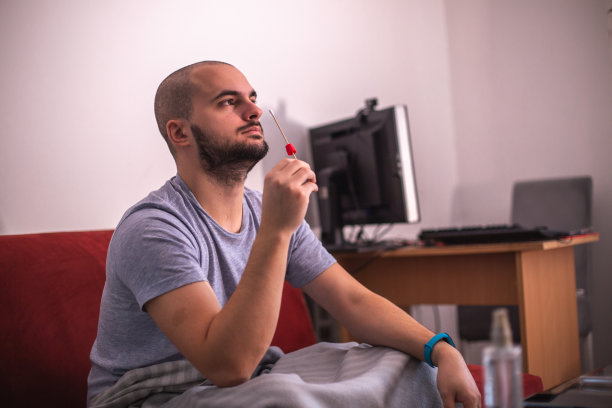 一名年轻男子在家中使用抗原试剂盒进行新冠病毒自我检测图片下载