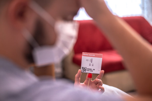一名年轻男子在家中使用抗原试剂盒进行新冠病毒自我检测图片下载