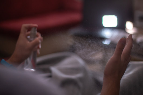 近景的人的手和消毒喷雾瓶在黑暗的背景。手卫生。冠状病毒疫情防控措施图片下载