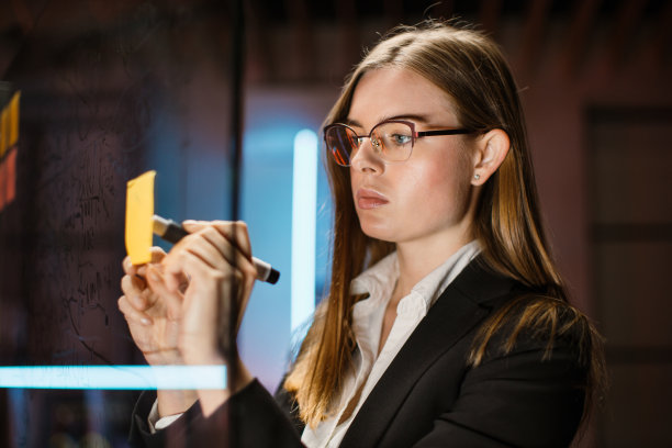 女商人在玻璃板上的便签纸上写下任务或创意图片下载