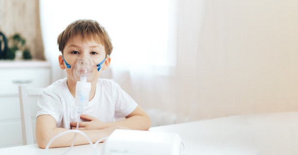 一个脸上戴着口罩的小男孩在呼吸药物图片下载