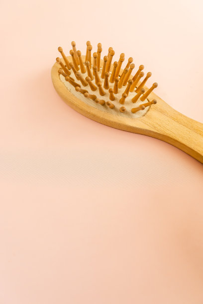 头发护理的概念。生态护发配件。木制头发刷粉红色的背景。健康美丽的头发。脱发的保护。头皮按摩。垂直图片下载