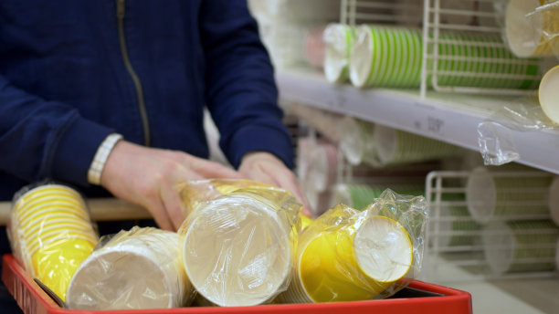 为聚会或生日而堆放在购物车中的一次性杯子的特写镜头。在商店里为学生聚会做准备时，他们收集了很多纸杯，准备在假期喝。图片下载