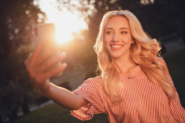 令人惊叹的积极波浪发型的照片女士使自拍录制视频晚上日落街道外图片下载