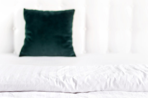 明亮的装饰软枕头在床的背景皮革绗缝床头板。祖母绿和橙色的枕头，部分床上特写，舒适。绗缝床头板背景，内部图片下载