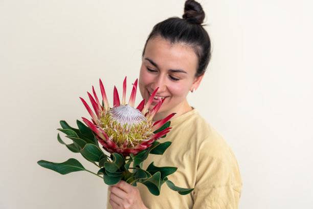 一个年轻的女人，在白色的背景上画着普罗塔花。图片下载