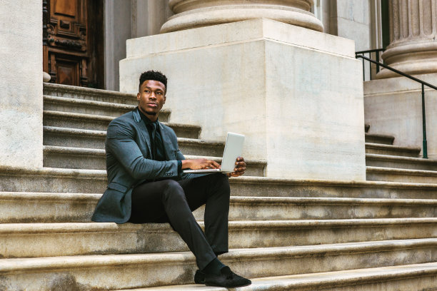 年轻的黑人商人在纽约办公大楼外用笔记本电脑工作图片下载