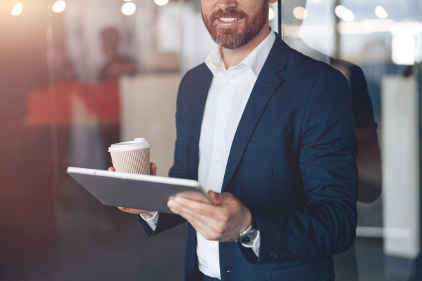 近距离微笑商人带走咖啡杯工作在笔记本电脑在现代办公室图片下载