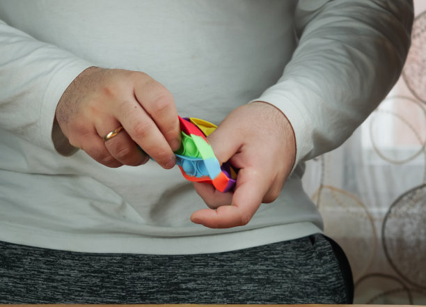 男人拿着减压玩具，手动娃娃玩具，隔离在窗帘背景上。图片下载