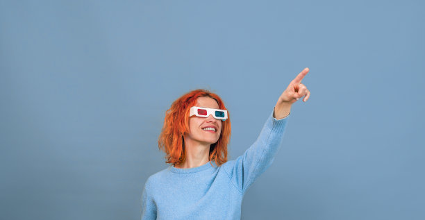 戴着3D眼镜的快乐年轻女人，她向上指着手指图片下载