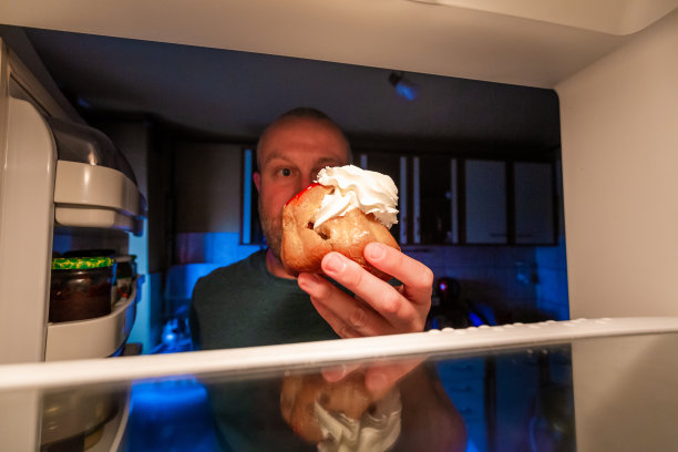 被冰箱里的奶油蛋糕诱惑的男人图片下载