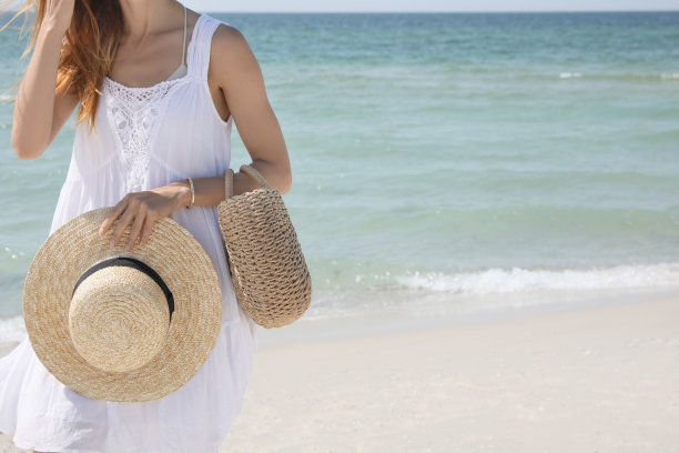 带沙滩包和草帽的女人在海边，特写图片下载